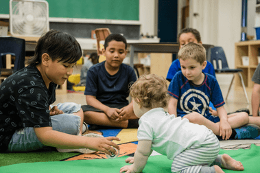 Boy reaching out to baby in Roots of Empathy program